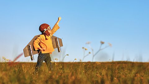 Child pilot aviator with wings of airplane dreams of traveling in summer at sunset