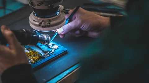 Alamy A technician repairing a mobile phone (Credit: Alamy)