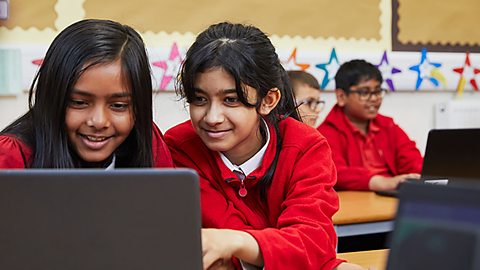 Two primary school pupils look at a laptop