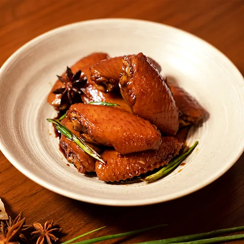 Black Sheep Staff When done cooking, Swiss chicken wings are coated in a caramelised sweet-soy sauce (Credit: Black Sheep Staff)