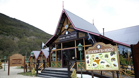 The Estacion del Fin del Mundo main building in Ushuaia, set against a backdrop of green hills.