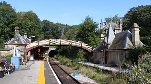 A view of Cromford Railway Station on a bright day. To the left is platform one, which is still in use today. To the right is the waiting room of the disused platform two, which served as the backdrop to the artwork for Oasis' Some Might Say single.