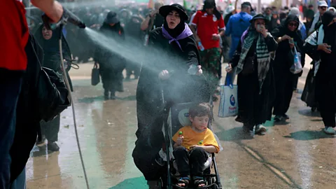 Getty Images A woman and child are sprayed with water to keep cool