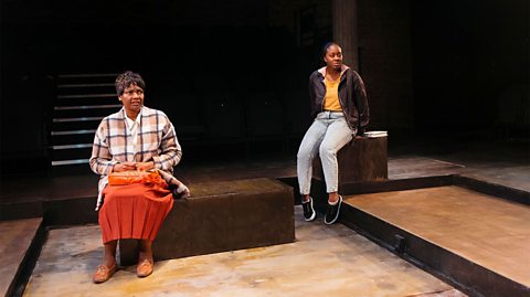 Two female actors on stage during a performance of Leave Taking.