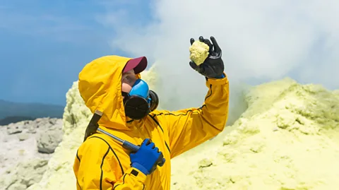 Getty Images A volcanologist inspects a rock amid sulphurous volcanism (Credit: Getty Images)