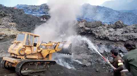 Getty Images Italian firefighters attempt to redirect lava at Mt Etna with water and machinery (Credit: Getty Images)