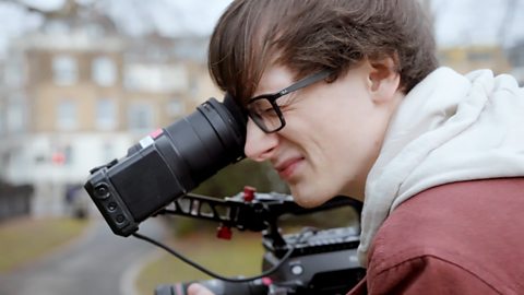 Director of Photography, Toby, looking through a camera lens.