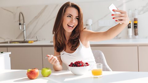 Woman takes a selfie while eating a bowl full of berries