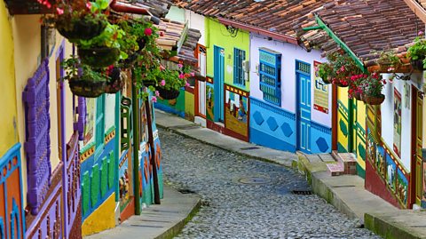 A cobbled winding street with colourful houses on each side. 