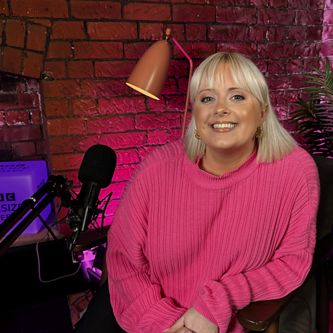 Katie Thistleton smiling to camera, sitting near a microphone.