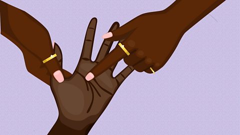 A pair of hands, wearing rings, pointing to the palm of another hand.