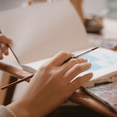 A young person painting in an art book.