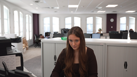 Katrina sitting down at her desk in front of a computer