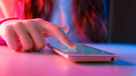 A person scrolling on their phone, which is placed on a table