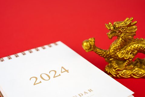 A statue of a golden dragon is placed next to a 2024 calendar.