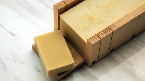 A slice of handmade soap made displayed on marble backdrop.