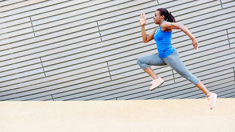 A woman wearing a blue top and blue leggings, having a run.