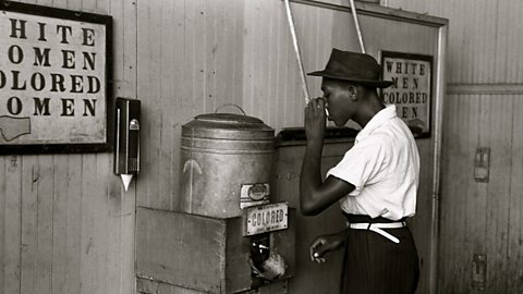 A man drinks from a segregated water fountain in 1939