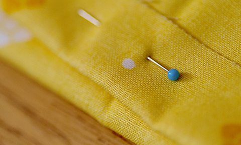 A bobble pin holding together two pieces of yellow patterned material