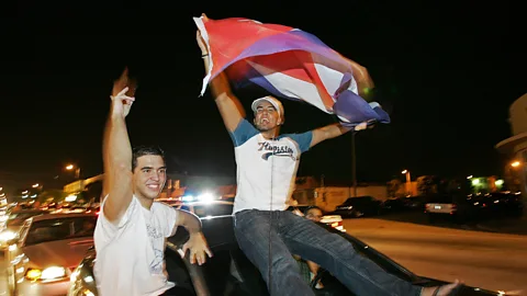 Getty Images People wave Cuban flags in the streets of Little Havana in Miami (Credit: Getty Images)