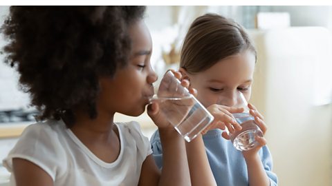 Two children each drinking a glass of water