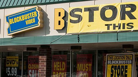 The sign of a Blockbuster shop, with signs for a closing down sale.