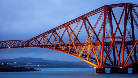 The Forth Bridge. Formed from many beams - triangle shapes are seen it its design as it stretches across the water supported by some towers.