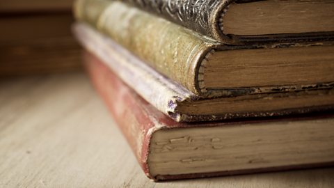 Four old books stacked on top of one another.