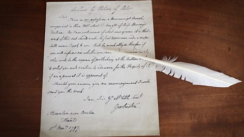 An old letter written by a quill and ink on a table.