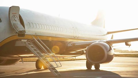 A passenger jet on the runway with its door open and a ladder leading to the open door.