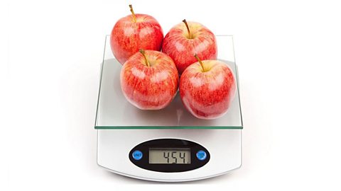 Four apples on a set of digital scales. The display reads four hundrend and fifty four grams.