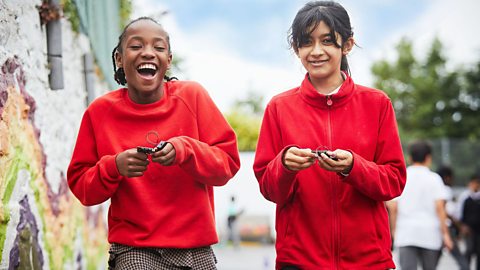 Two primary school children smiling while holding ý micro:bits