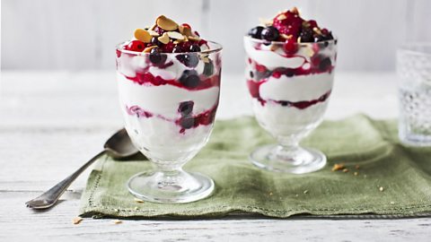 Two dessert glasses filled with yogurt and berries