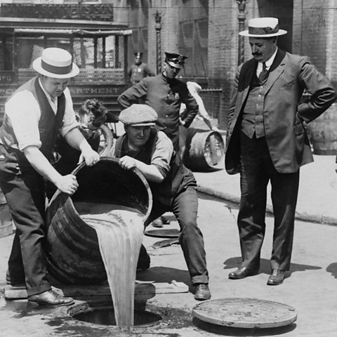 Prohibition in the USA 1920 - 1933: A barrel of confiscated illegal beer being poured down a drain.