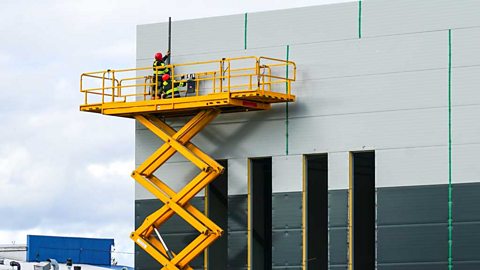 Workers on a scissor lift platform working on a building construction.