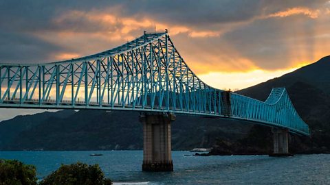 The Ikitsuki Bridge. A blue steel truss bridge spanning a large river, resting on stone columns.