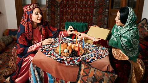 GeckoPhotos/Getty Images Azeri women and Novruz tray with traditional pastries