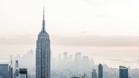 A photograph of the New York skyline with the Empire State Building rising above a misty city.