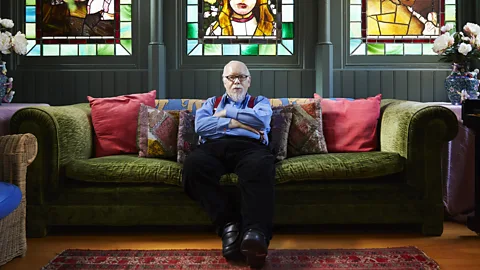 Luke Andrew Walker British Pop artist sitting on sofa with stained glass window in background  (Credit: Luke Andrew Walker)