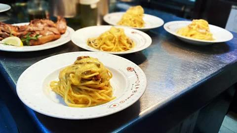 Andrea Carlo Martinez Four plates of carbonara in Armando al Pantheon’s kitchen, waiting to be topped with a healthy shaving of cheese (Credit: Andrea Carlo Martinez)