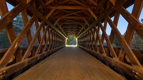 A view from inside a covered wooden truss footbridge.