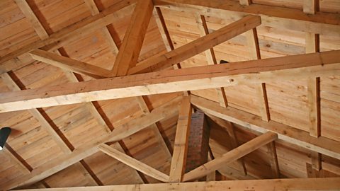 A timber framed ceiling with triangular trusses, beams and columns