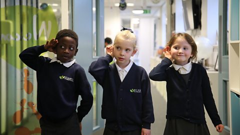 3 kids in school uniform cupping their ears