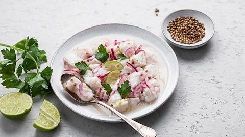 A plate of ceviche served with lime and coriander 