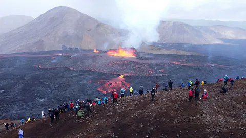 Getty Images Tourists watching lava flow from rim of volcano