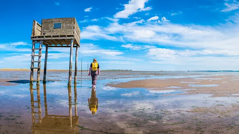 Getty Images The ancient Pilgrim’s Way from the mainland to Holy Island is signposted by wooden poles (Credit: Getty Images)