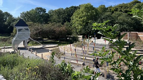 An aerial view of the nature playground in Copenhagen with coloured sticks, rocks and an artisticly designed slide.