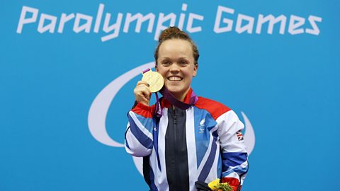 Ellie Simmonds holding up a gold medal at the Paralympic Games