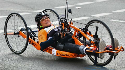 A female athlete using an orange handcycle