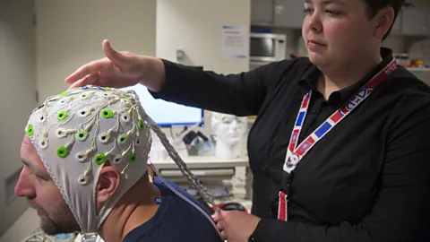 Getty Images A researcher adjusting an EEG cap on the head of former NHL player Bryan Muir (Credit: Getty Images)